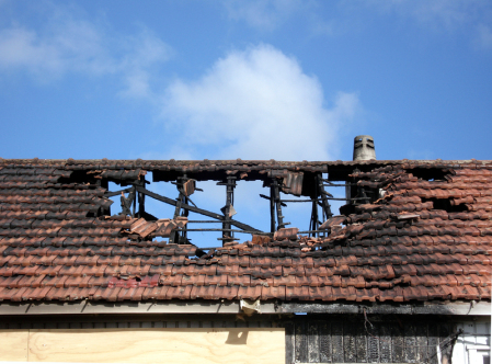 Fire damage to a home burning through the ceiling, roof framing and roof